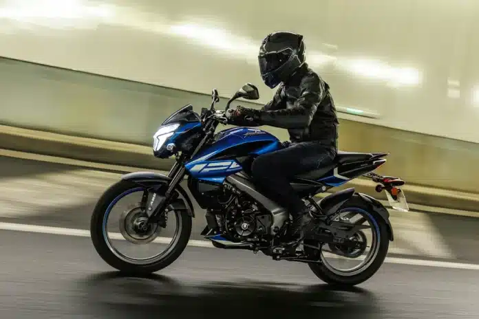 Vista lateral dinámica de la Pulsar NS 125 2026 rodando en entorno urbano nocturno.