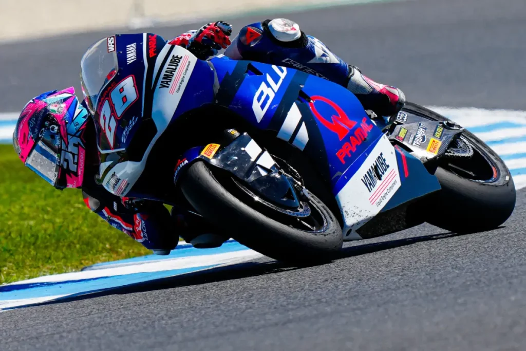 Izan Guevara inclinado sobre su moto de Moto2 durante una sesión en pista