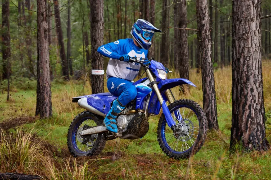 Yamaha WR450F 2027 en color Icon Blue circulando por una zona boscosa