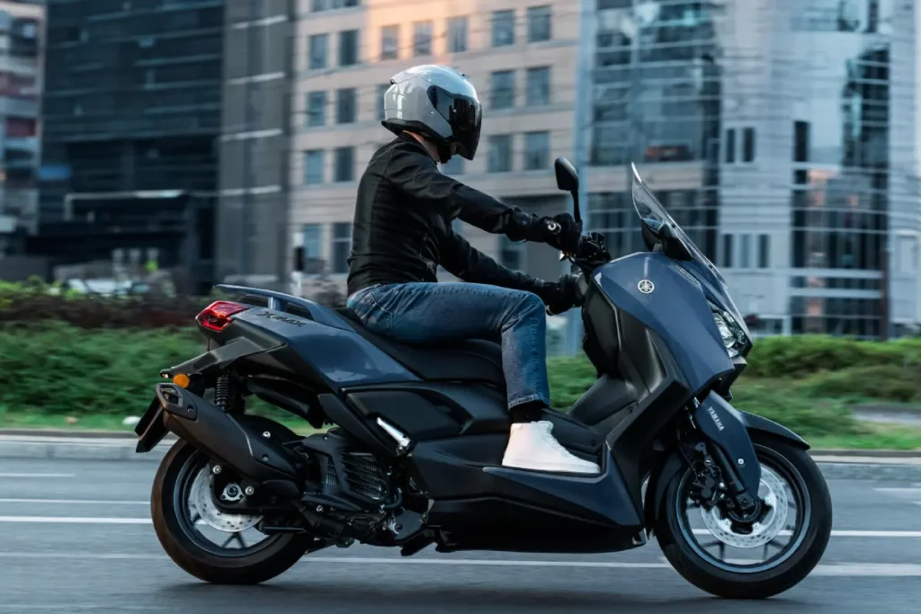 Yamaha XMAX 125 Tech MAX 2027 en color Avio Blue circulando por ciudad